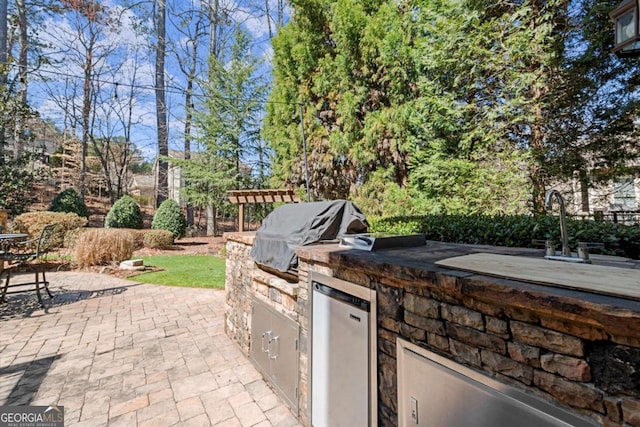 view of patio with area for grilling, a grill, and a sink