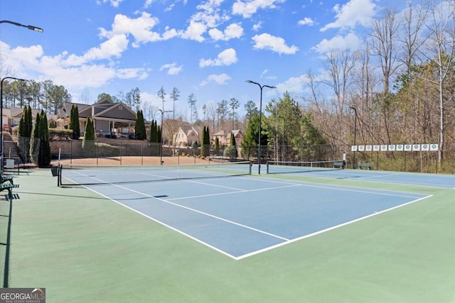 view of tennis court featuring community basketball court and fence