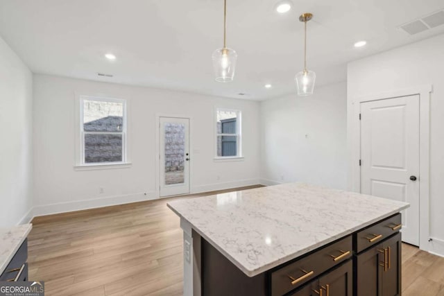 kitchen featuring visible vents, a healthy amount of sunlight, hanging light fixtures, and light wood finished floors