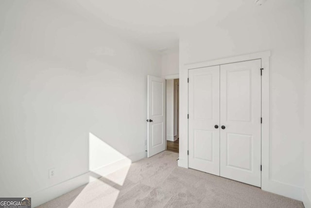 unfurnished bedroom with a closet and light colored carpet