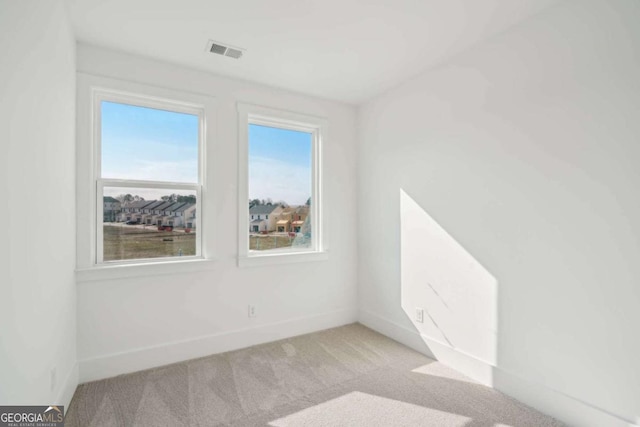 empty room featuring baseboards, visible vents, a wealth of natural light, and light carpet