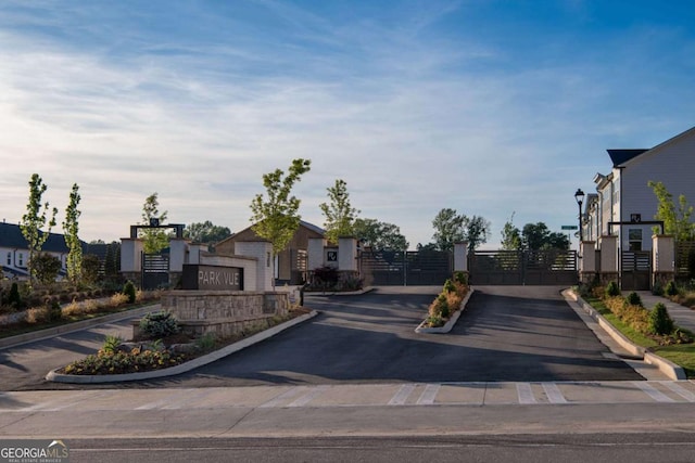 view of street featuring a gated entry, curbs, street lights, and a gate