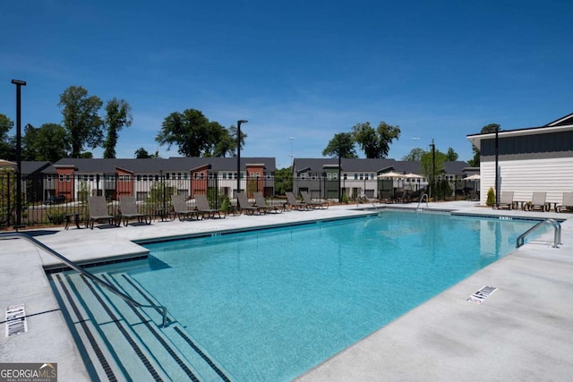 pool featuring a residential view, a patio, and fence