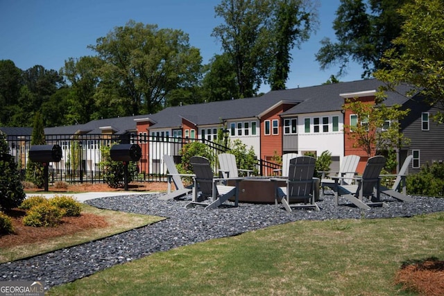 rear view of house featuring a fire pit, fence, a residential view, a yard, and a patio area