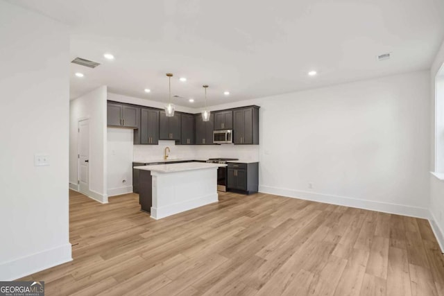 kitchen with light wood-type flooring, a kitchen island, recessed lighting, stainless steel appliances, and light countertops