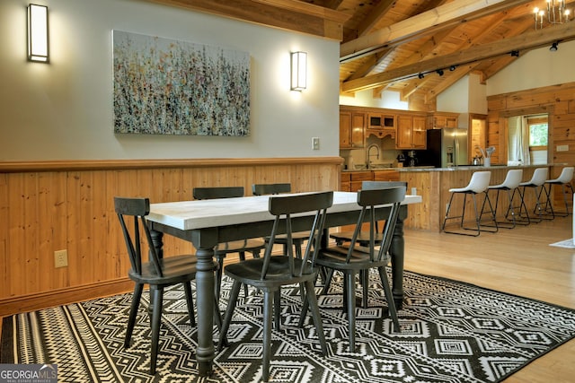 dining area with light wood finished floors, wooden walls, and a healthy amount of sunlight