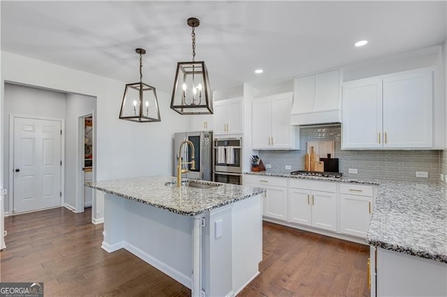 kitchen featuring tasteful backsplash, premium range hood, dark wood finished floors, appliances with stainless steel finishes, and a sink