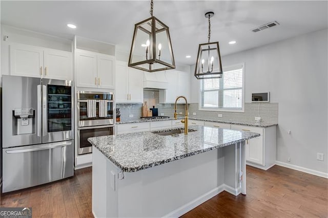 kitchen featuring visible vents, dark wood finished floors, a sink, stainless steel appliances, and white cabinetry