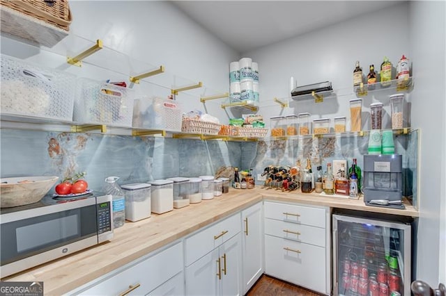 bar featuring beverage cooler, stainless steel microwave, and a bar