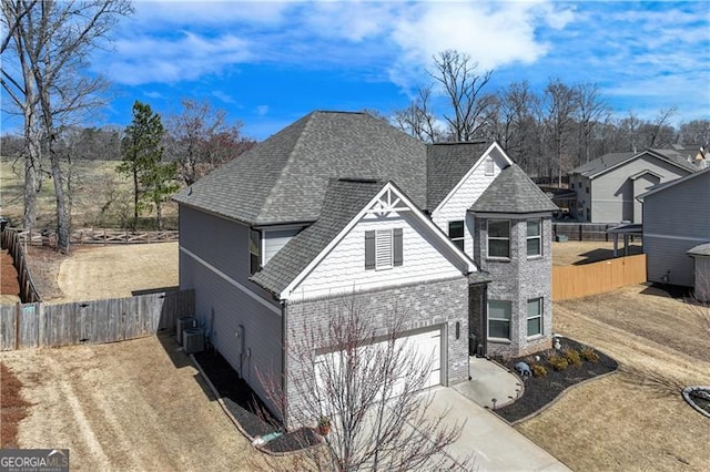 view of front of home featuring fence, driveway, a shingled roof, a garage, and brick siding