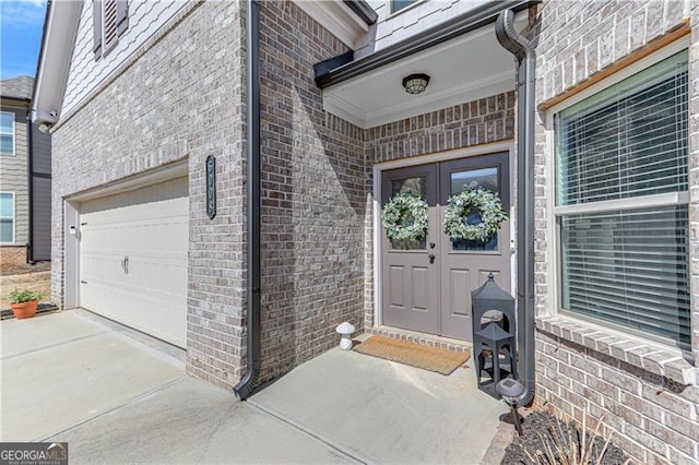 view of exterior entry with brick siding, driveway, an attached garage, and french doors