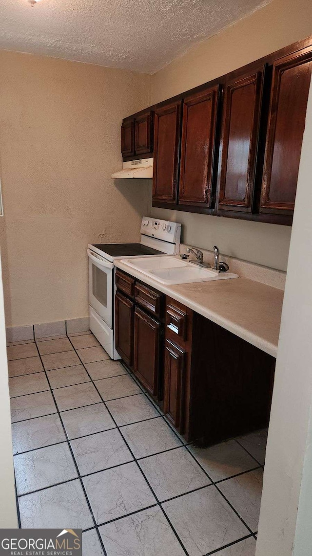 kitchen featuring a sink, light countertops, dark brown cabinetry, under cabinet range hood, and white range with electric stovetop