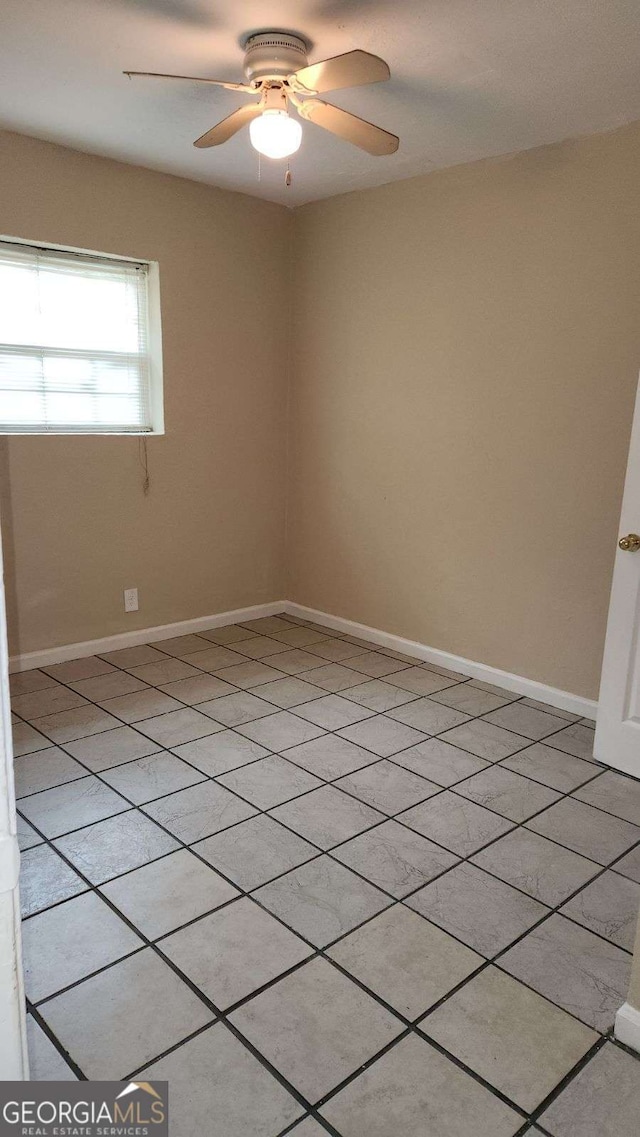 spare room with baseboards and a ceiling fan