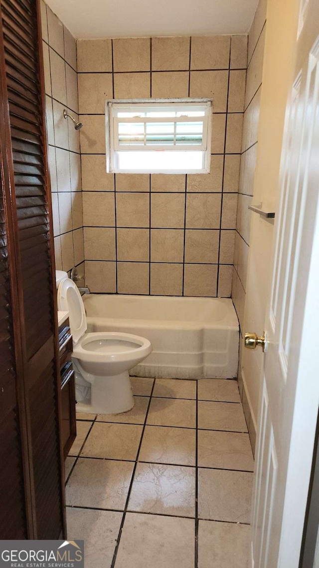 bathroom featuring tile patterned floors, toilet, and washtub / shower combination