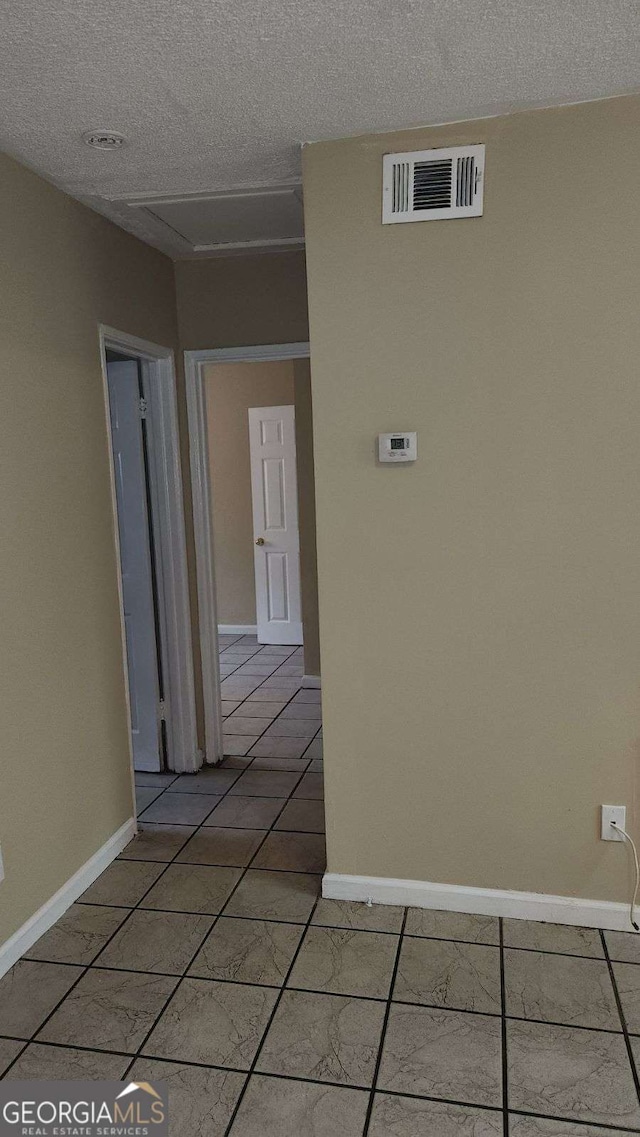 hallway with visible vents, a textured ceiling, and baseboards