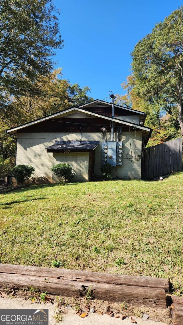 rear view of house with concrete block siding, a yard, and fence