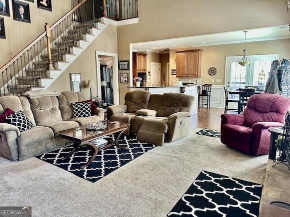 living area with stairway, a high ceiling, and wood finished floors