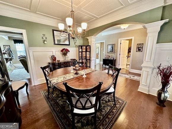 dining space featuring coffered ceiling, dark wood finished floors, decorative columns, arched walkways, and wainscoting