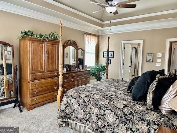 bedroom featuring a ceiling fan, a raised ceiling, light colored carpet, and ornamental molding