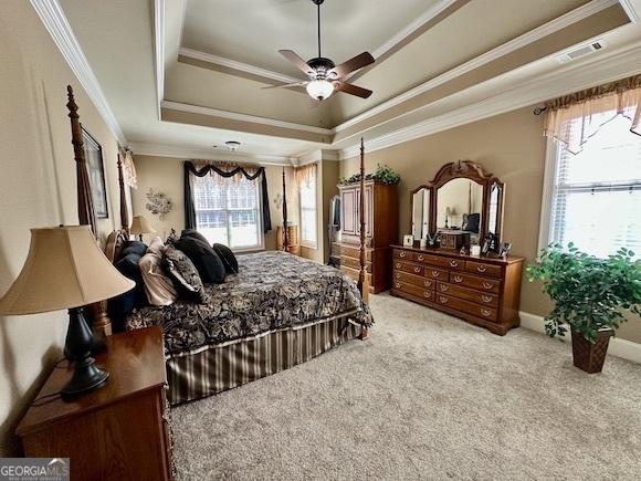 bedroom featuring a tray ceiling, baseboards, carpet, and crown molding