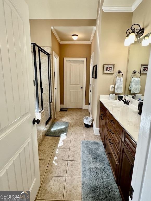 bathroom featuring tile patterned floors, a stall shower, ornamental molding, baseboards, and vanity