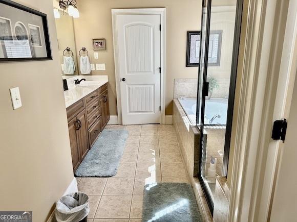 bathroom with a bath, vanity, and tile patterned flooring