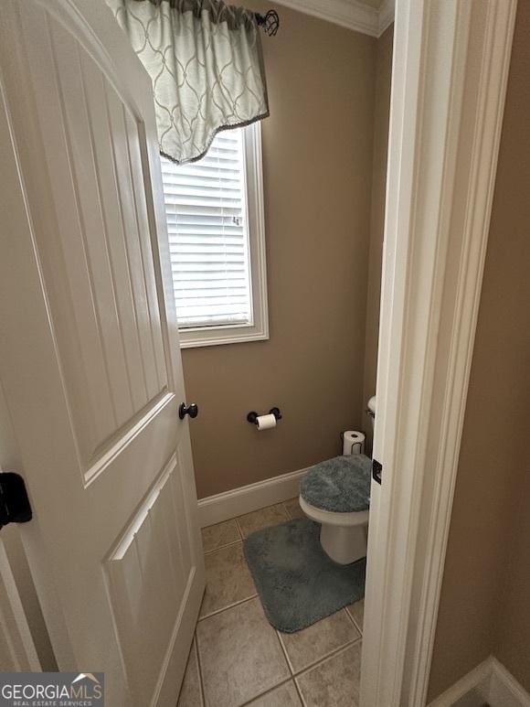 bathroom with tile patterned flooring, toilet, baseboards, and ornamental molding