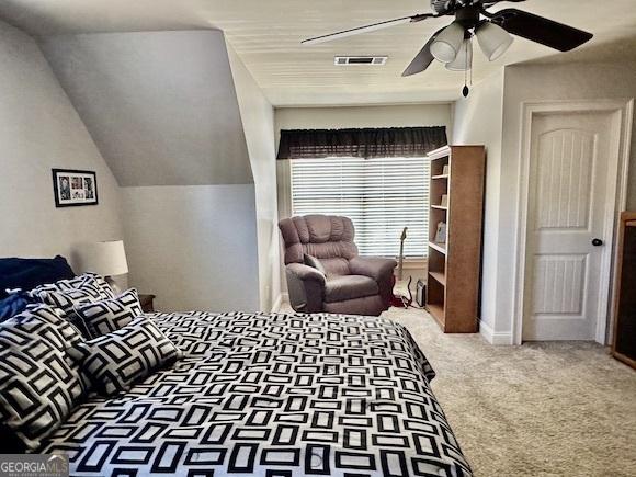 carpeted bedroom featuring visible vents, lofted ceiling, and ceiling fan