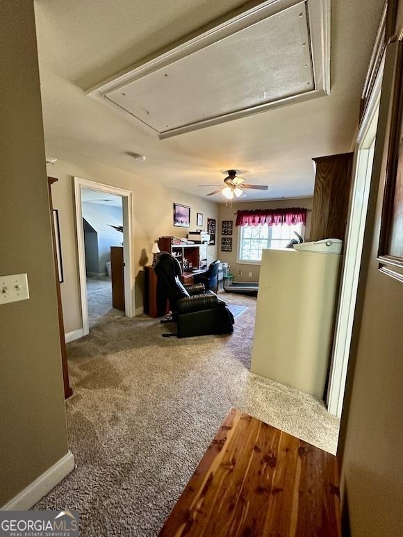 carpeted living room with attic access and baseboards