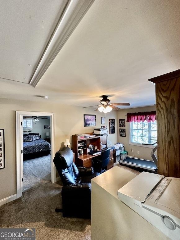 carpeted living area with baseboards and ceiling fan