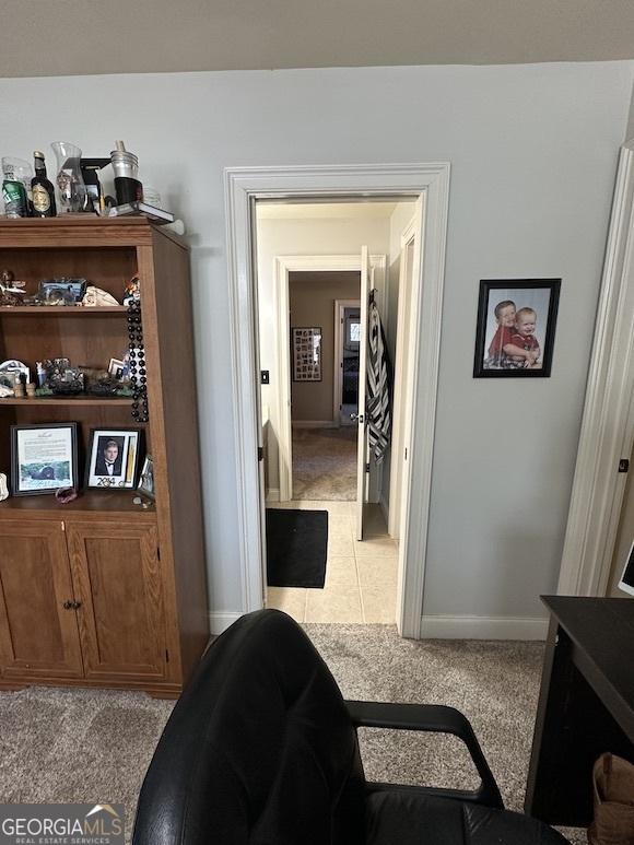 hall featuring tile patterned floors, baseboards, and carpet