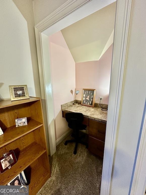 office space with vaulted ceiling, carpet flooring, and built in study area