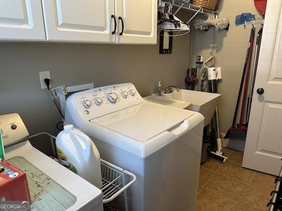 clothes washing area featuring tile patterned floors, cabinet space, and washer and clothes dryer