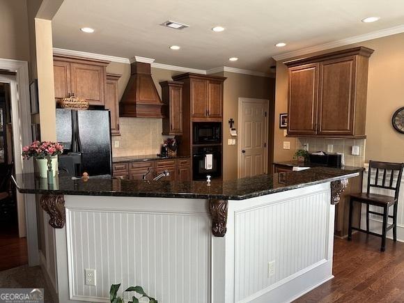 kitchen with visible vents, crown molding, custom range hood, black appliances, and dark wood-style flooring