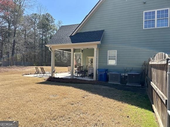 back of house with a patio area, central AC unit, a lawn, and roof with shingles