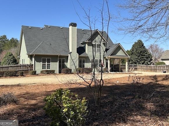 back of house featuring fence and a chimney