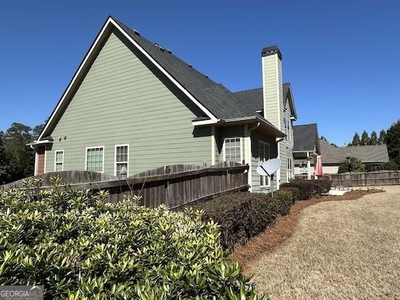 view of side of home with a chimney and fence