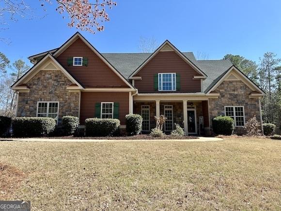 craftsman-style house with stone siding and a front lawn