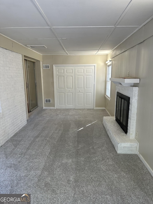 unfurnished living room featuring visible vents, a brick fireplace, brick wall, and carpet