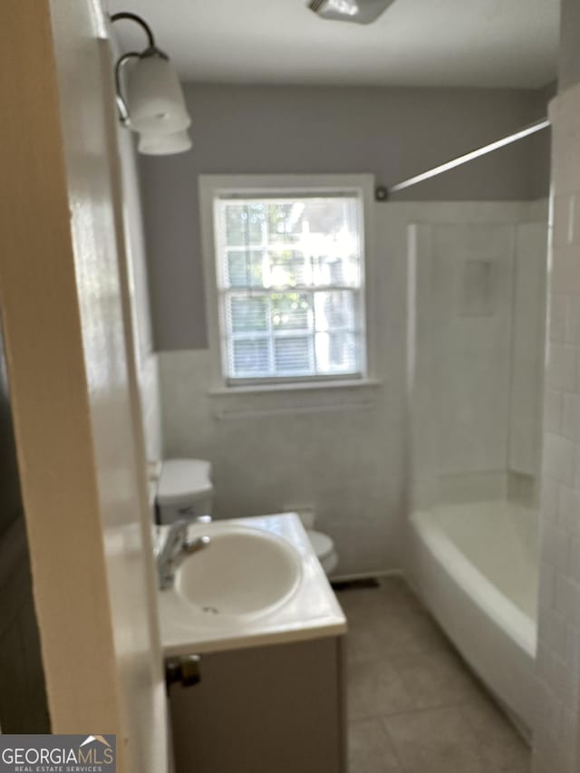 bathroom with toilet, vanity, and tile patterned flooring