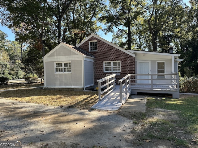 view of front facade with brick siding and a wooden deck