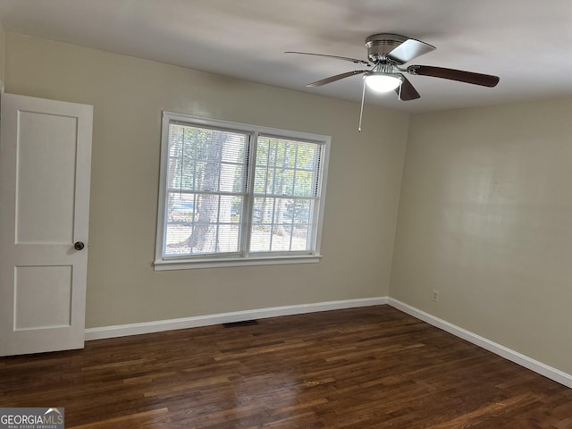 spare room featuring a ceiling fan, visible vents, baseboards, and dark wood-style flooring