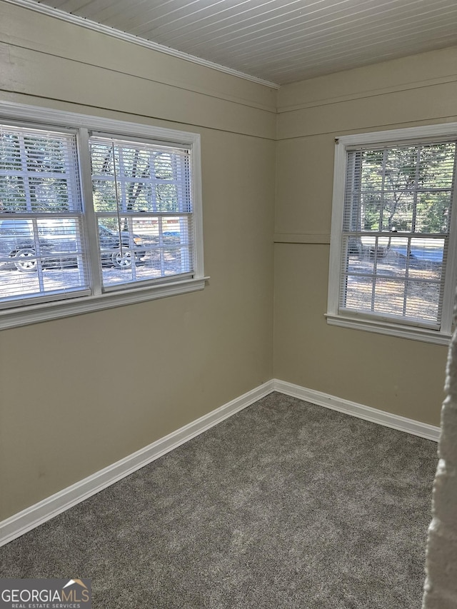 unfurnished room featuring baseboards and dark carpet