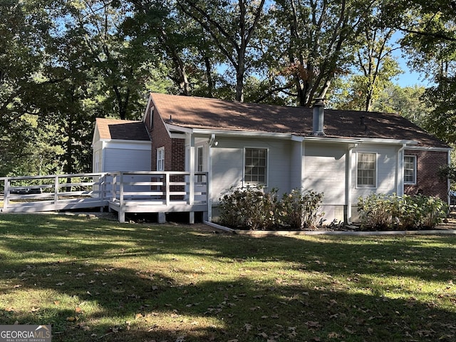 view of property exterior featuring brick siding, a deck, and a lawn