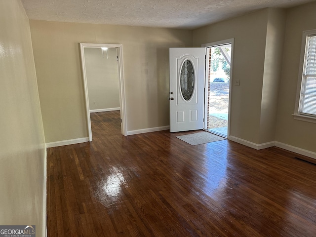 entryway featuring visible vents, baseboards, dark wood-type flooring, and a textured ceiling