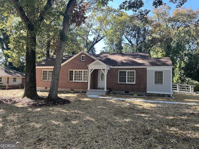 view of front of property featuring crawl space, brick siding, and fence