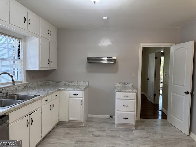 kitchen featuring baseboards, a sink, light countertops, white cabinets, and stainless steel dishwasher