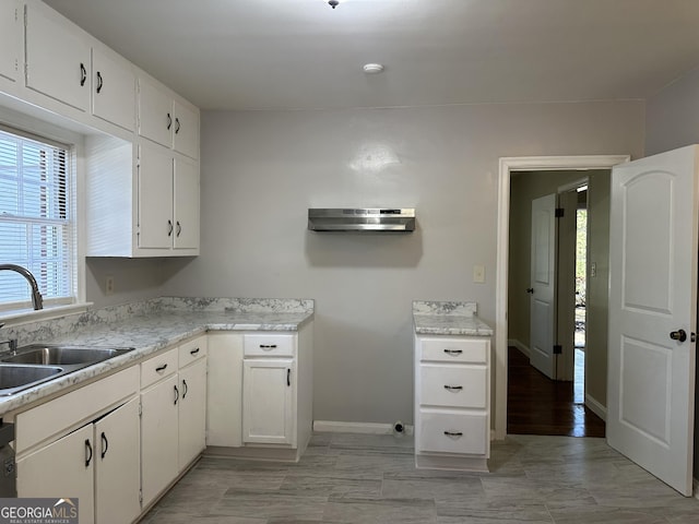 kitchen with white cabinetry, light countertops, and a sink