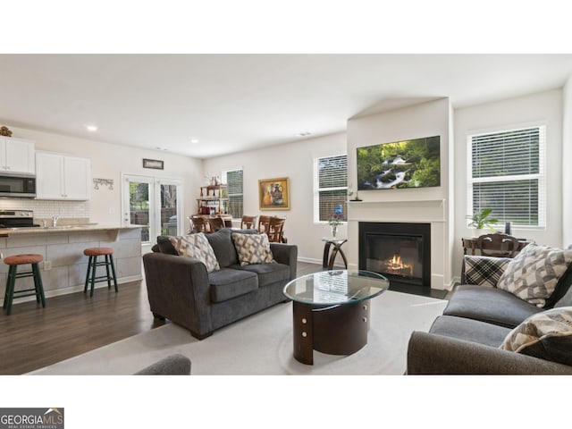 living area featuring recessed lighting, baseboards, a glass covered fireplace, and wood finished floors