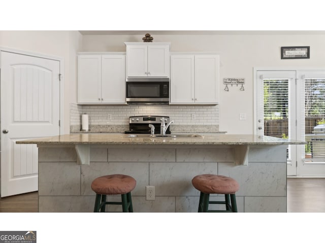 kitchen with stainless steel appliances, a kitchen bar, and backsplash